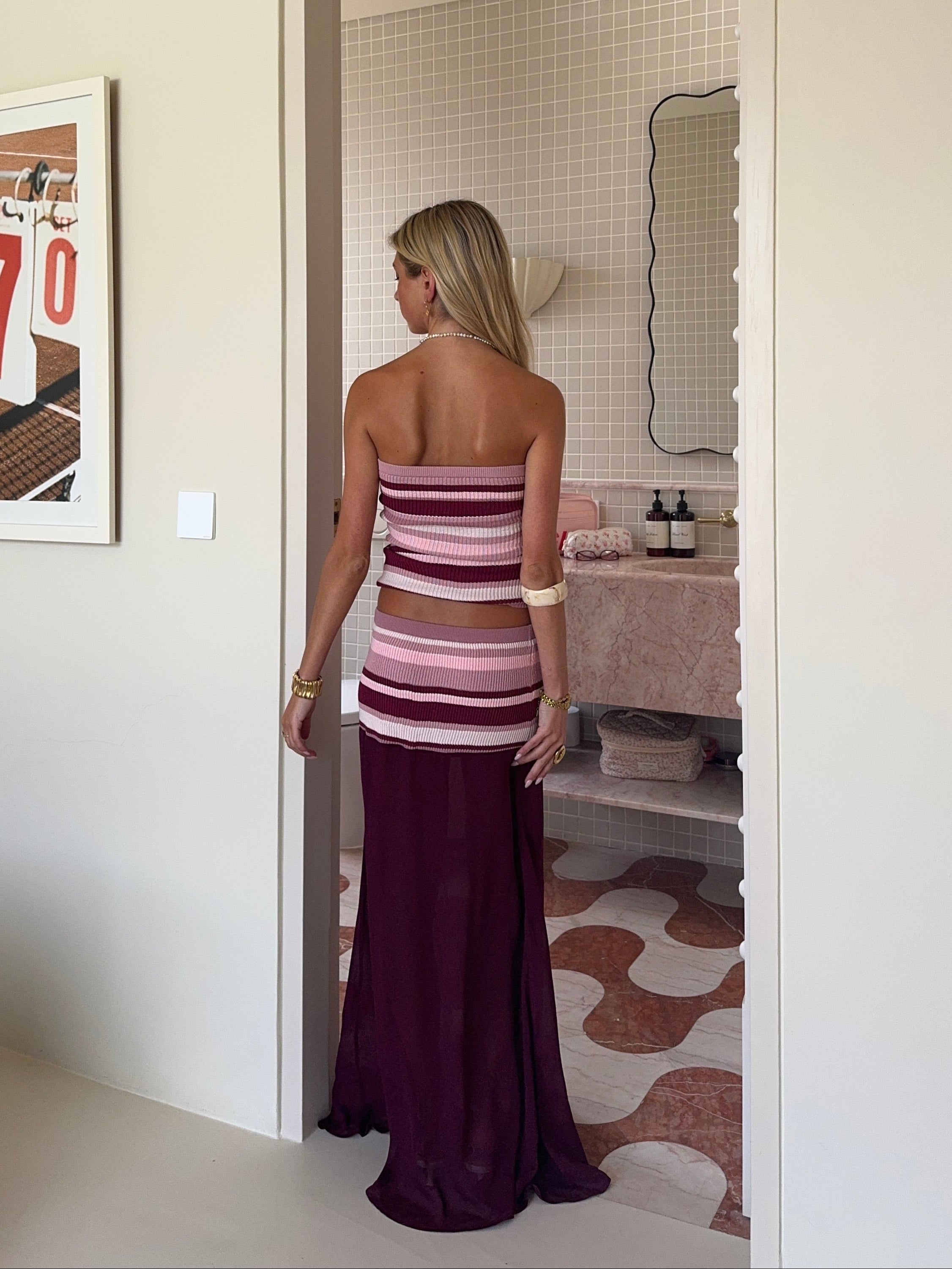Woman in a striped dress standing in a bathroom.